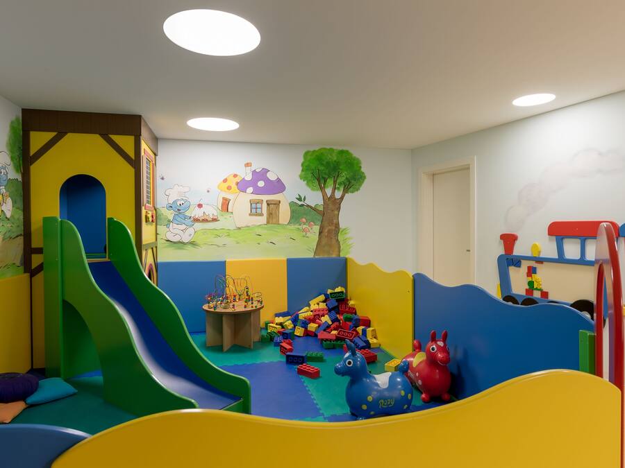 Un espace de jeux pour enfants avec un toboggan, des structures de jeu et une fresque murale.
