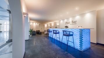 A pool bar area with a reception desk, three bar stools, and a potted plant.