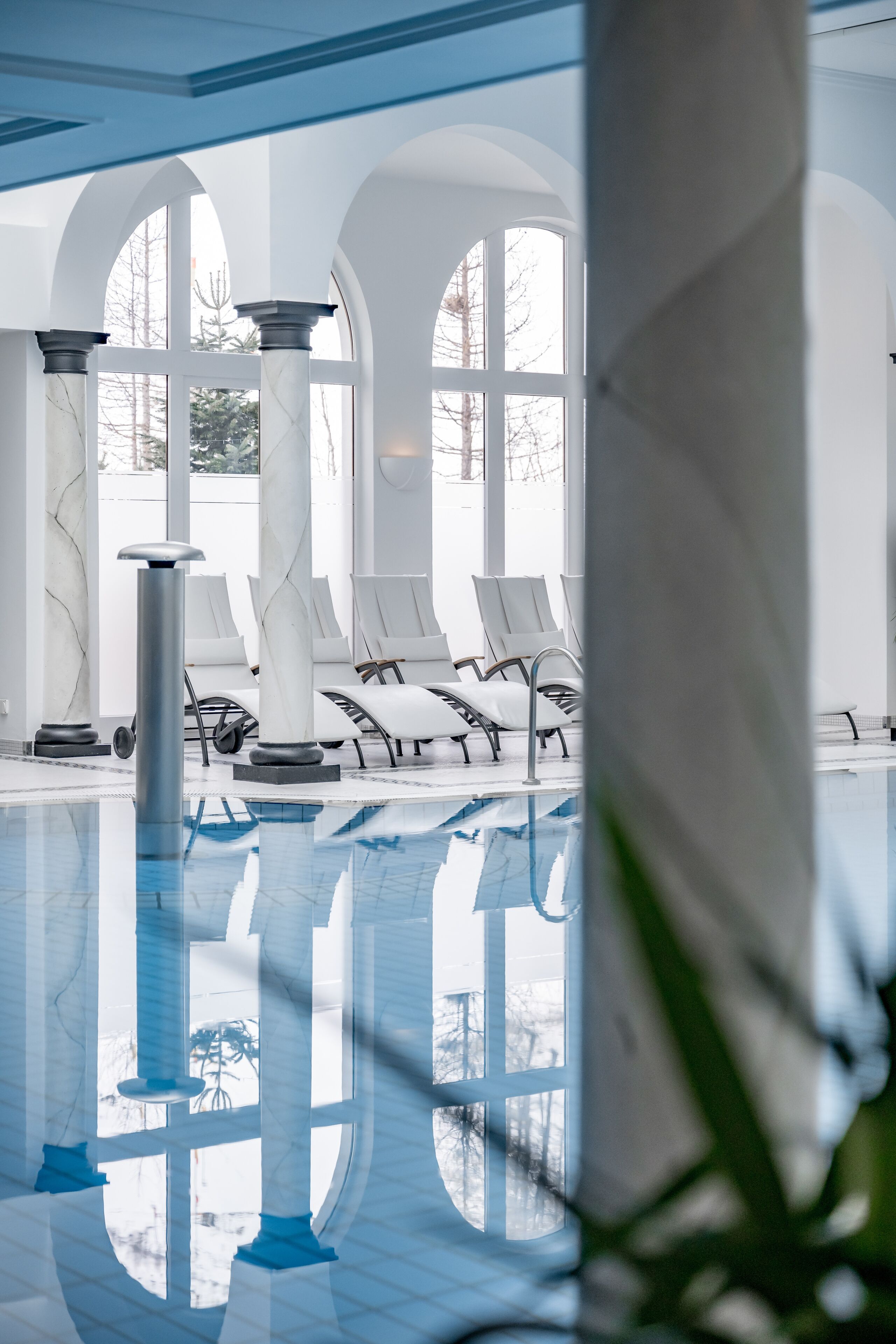 Ein Poolbereich mit weißen Säulen und Liegestühlen.