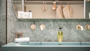 A bathroom with a marble backsplash, a sink with a towel, and toiletries on the counter.
