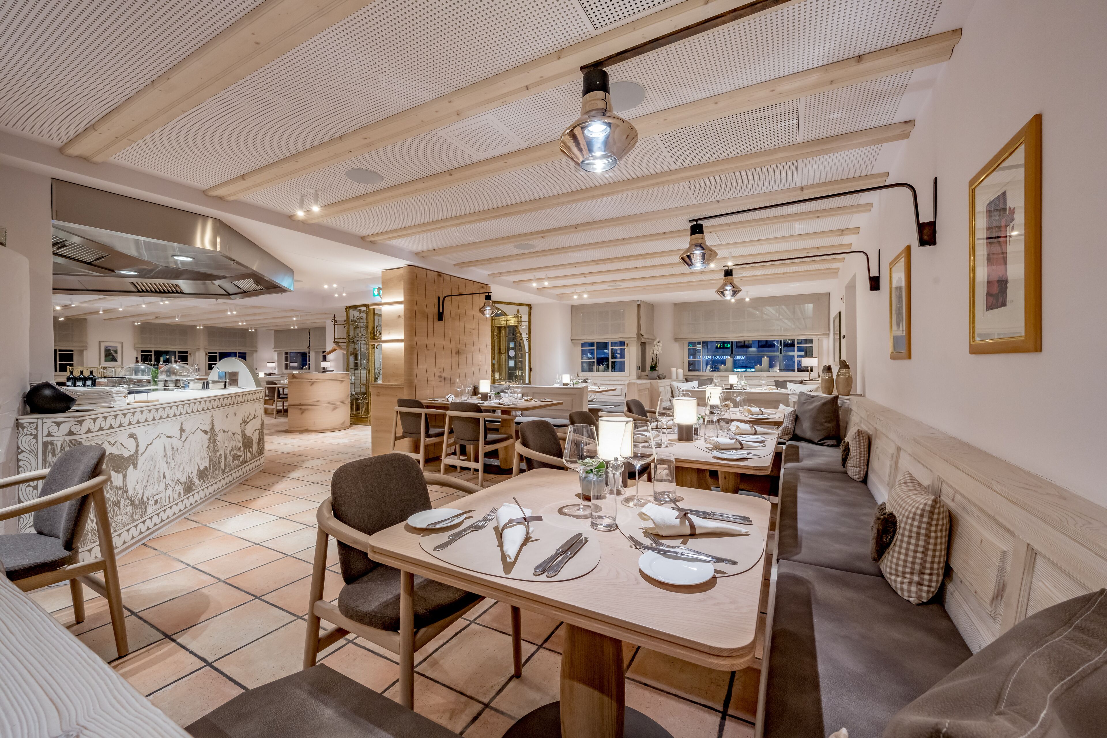 Un restaurante moderno con vigas de madera en el techo, pisos de baldosas y una combinación de mesas y zonas de estar.