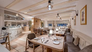 Un restaurante moderno con vigas de madera en el techo, pisos de baldosas y una combinación de mesas y zonas de estar.
