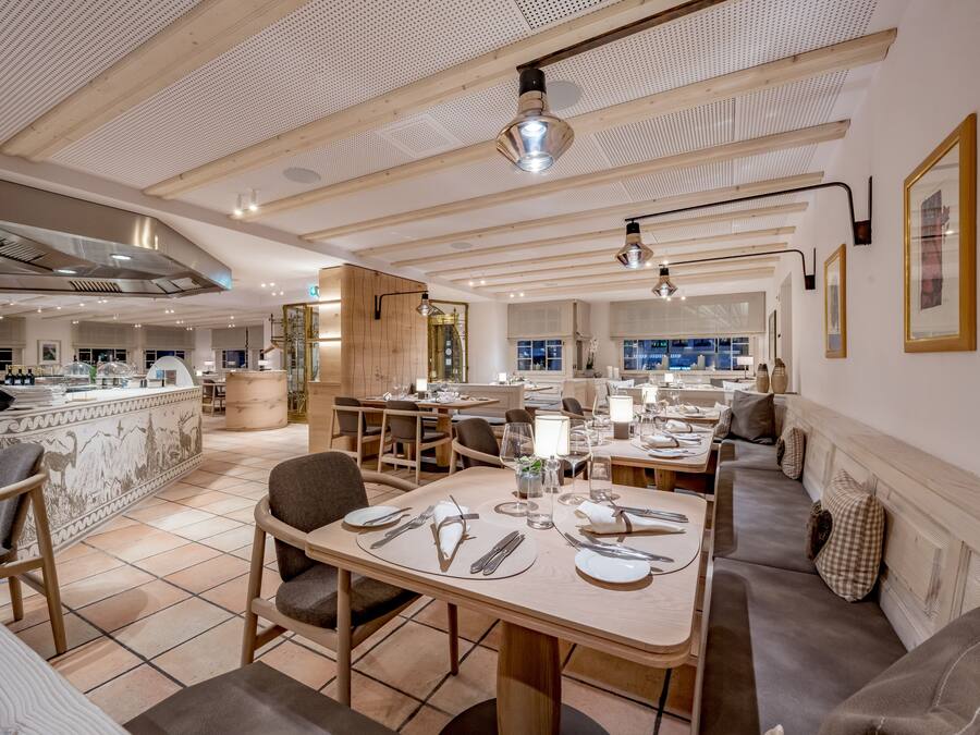 Un restaurante moderno con vigas de madera en el techo, pisos de baldosas y una combinación de mesas y zonas de estar.