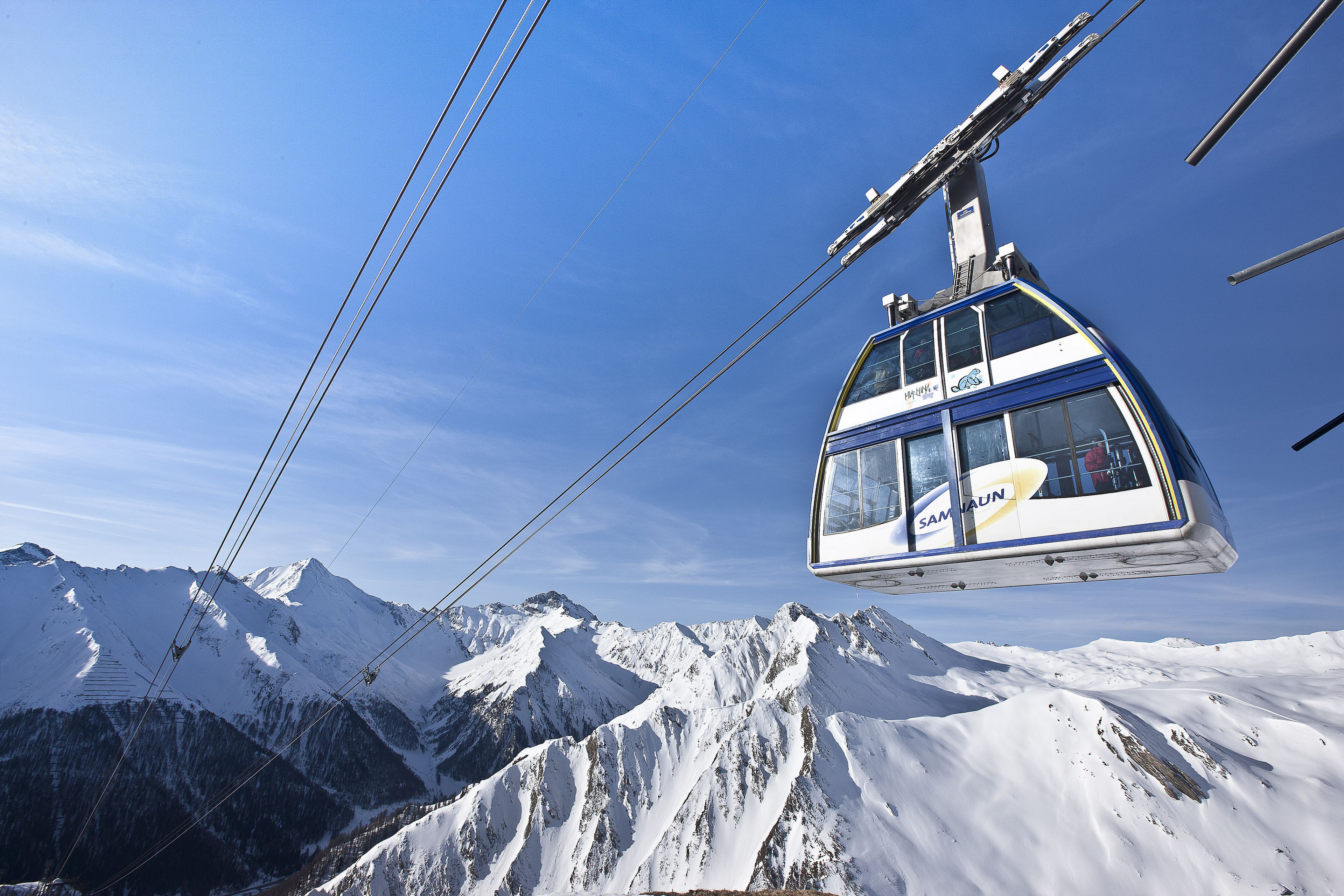 Eine Seilbahn mit freiem Blick auf schneebedeckte Berge im Hintergrund.