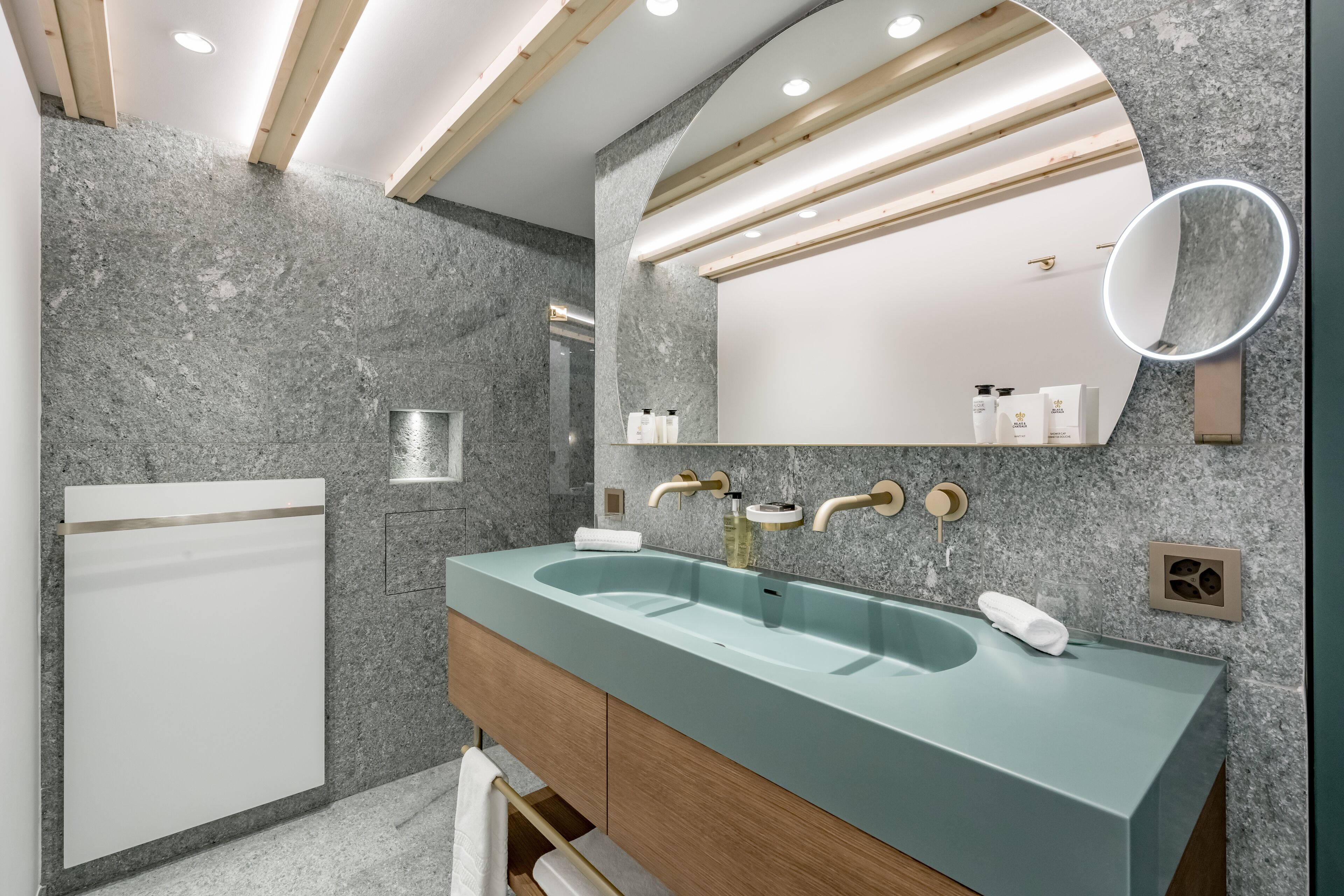 A modern bathroom with a double sink, wooden cabinets, and a large mirror.