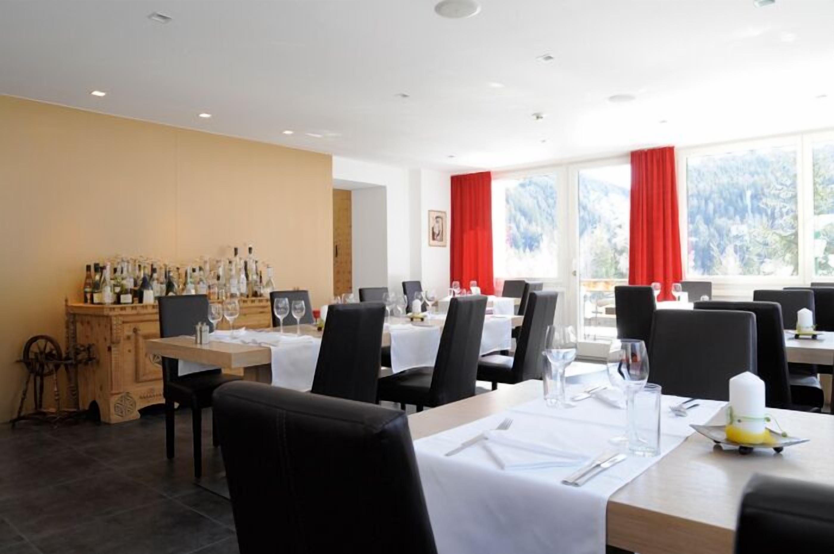 A restaurant with tables set for dining, a wine rack, and a view of the outdoors.