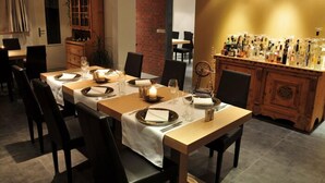 A dining area with a long table set for six, surrounded by chairs. A wooden cabinet with glass doors is visible in the background. - Hotel Filli (Scuol)