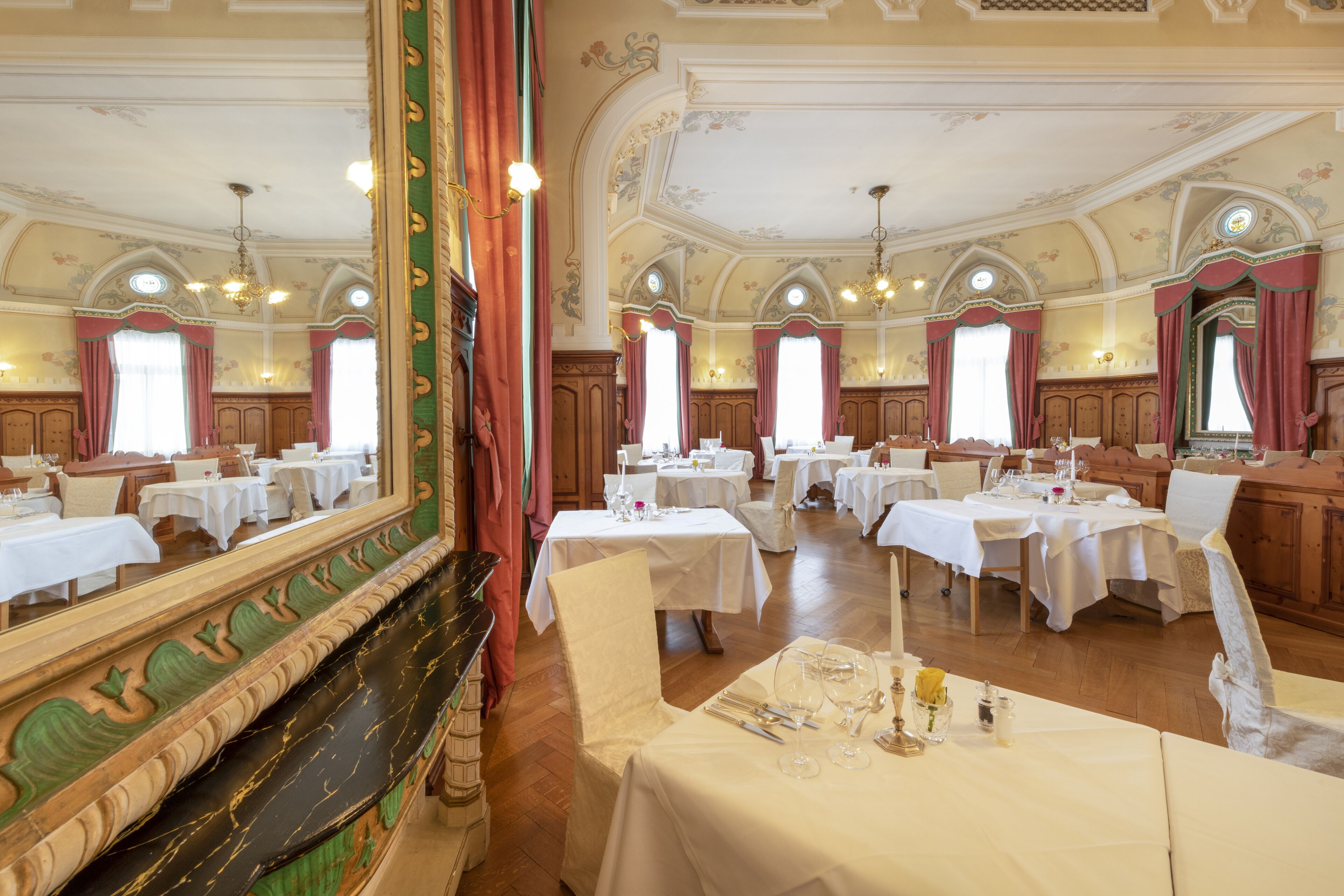 Een statig eetzaal met meerdere gedekte tafels, een vleugelpiano en decoratieve wandornamenten.