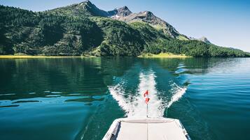 A boat on a calm lake with mountains in the background.