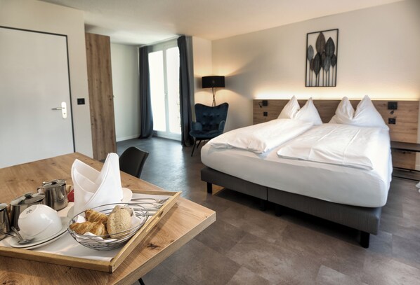 A hotel room with a bed, bedside table, lamp, and a view of the hallway.