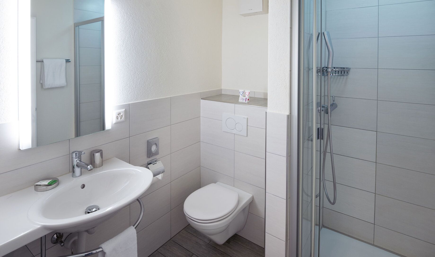 Une salle de bain moderne avec un lavabo blanc, des toilettes et une douche à parois de verre.