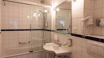 A modern bathroom with a glass-enclosed shower, a sink with a mirror, and a hairdryer on a counter.