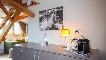 Une chambre moderne avec un meuble gris, une machine à café et une lampe de table.