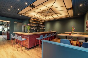 A modern bar area with a wooden counter, bar stools, and a seating area with tables and chairs. - b_smart hotel Schönenwerd (Schonenwerd)
