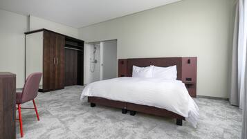 A hotel room with a bed, a desk, a chair, and a wardrobe.