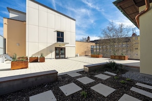 A modern building with a flat roof, large windows, and a paved courtyard with planters and benches. - b_smart hotel Schönenwerd (Schonenwerd)