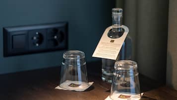 Una habitación oscura con una lámpara de pared y tres botellas de vidrio sobre una superficie de madera.