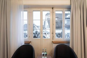 Una stanza con vista, illuminata da ampie porte in vetro, due sedie e due bottiglie su un tavolino.