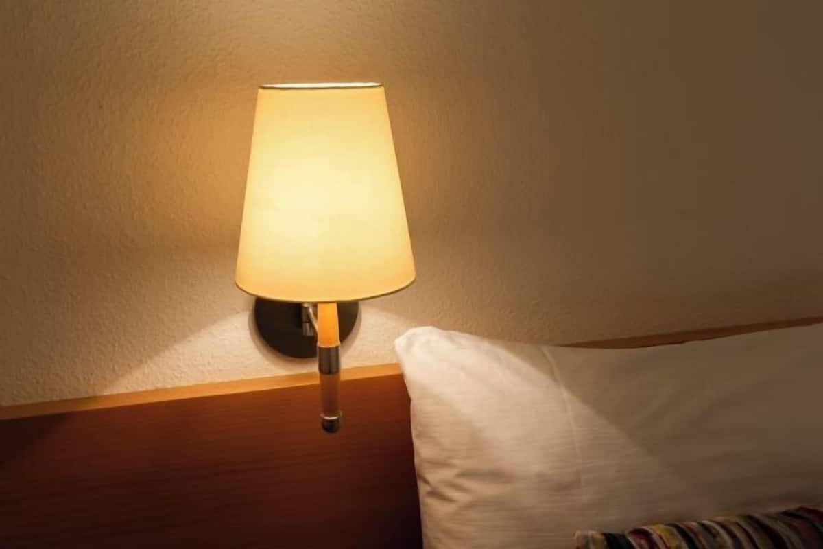 A lamp on a bedside table next to a white pillow.