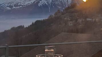 A table set for two with a view of snow-capped mountains and a sunset.