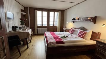 A bedroom with a bed, bedside table, lamp, and a desk with a chair.