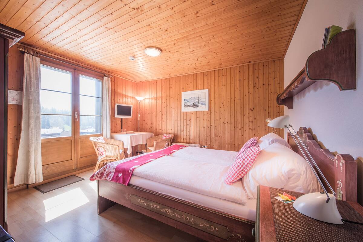 Una habitación con paneles de madera, una cama, un escritorio y una silla.