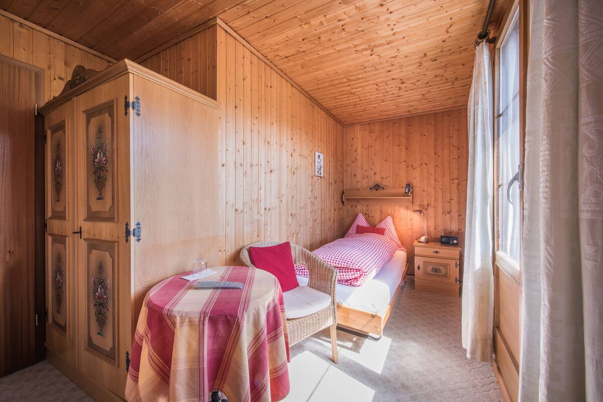 Una habitación de cabaña de madera con una cama, una mesa y una silla.