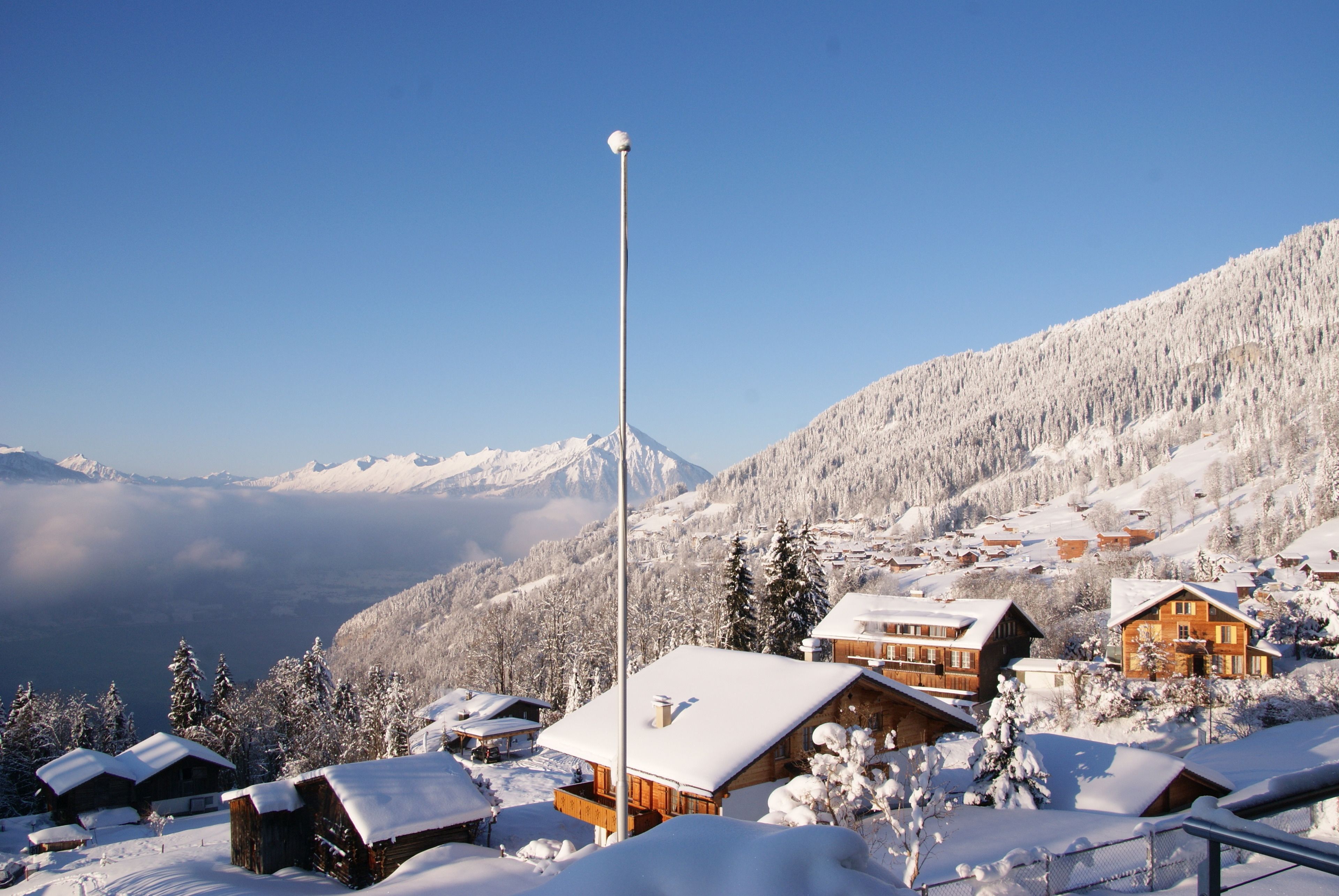 Un pueblo en la montaña cubierto de nieve, con cabañas de madera y un cielo despejado.