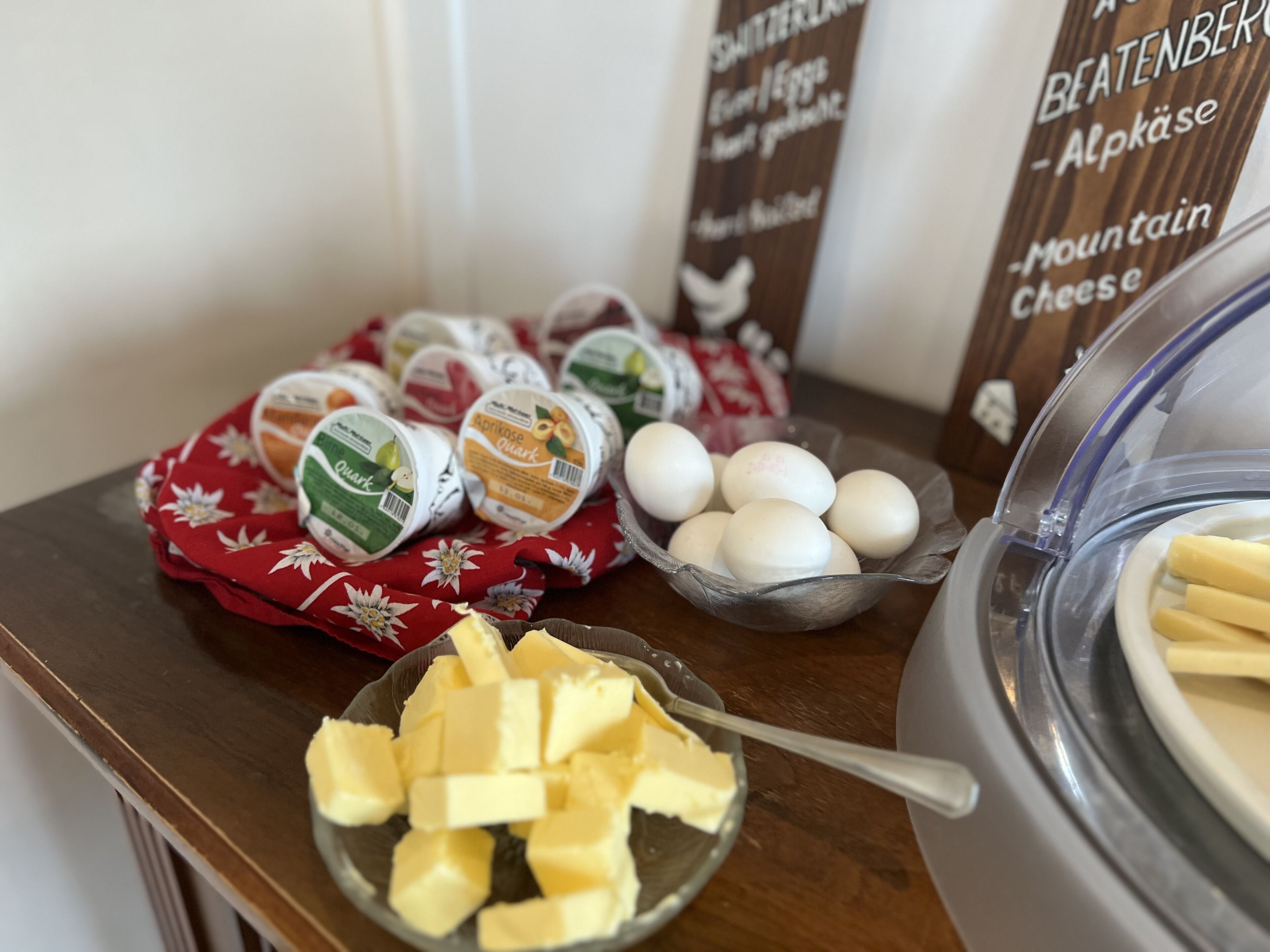 Una mesa con diversos alimentos, incluyendo queso quark, huevos y mantequilla.