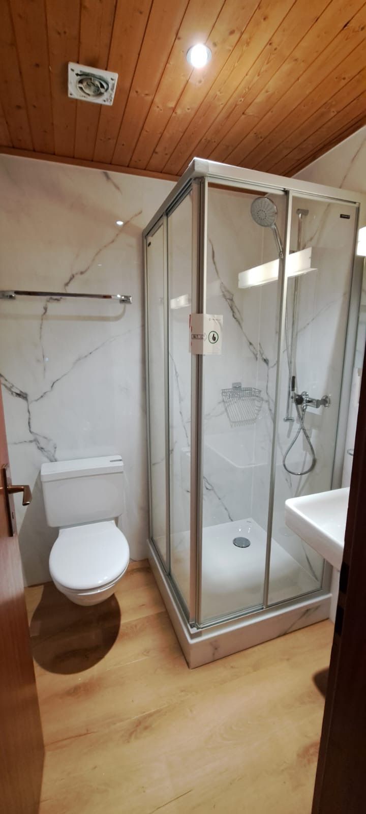 A bathroom with a glass-enclosed shower, a toilet, and a sink.