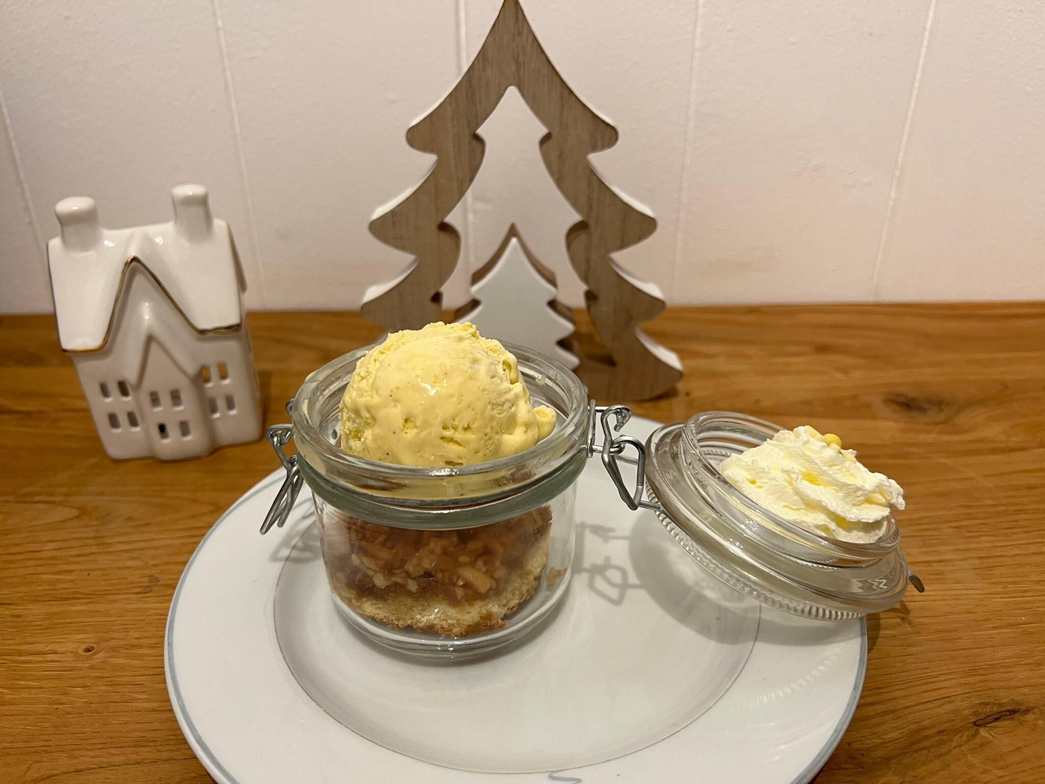 A dessert with a scoop of ice cream and a jar of whipped cream on a plate.