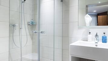 A modern bathroom with a glass-enclosed shower, a white sink, and a mirror above the sink.