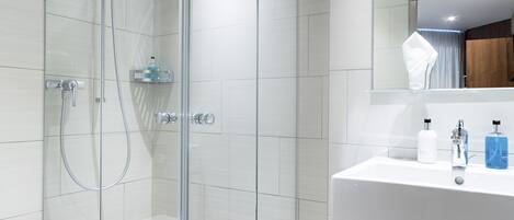 A modern bathroom with a glass-enclosed shower, a white sink, and a mirror above the sink.