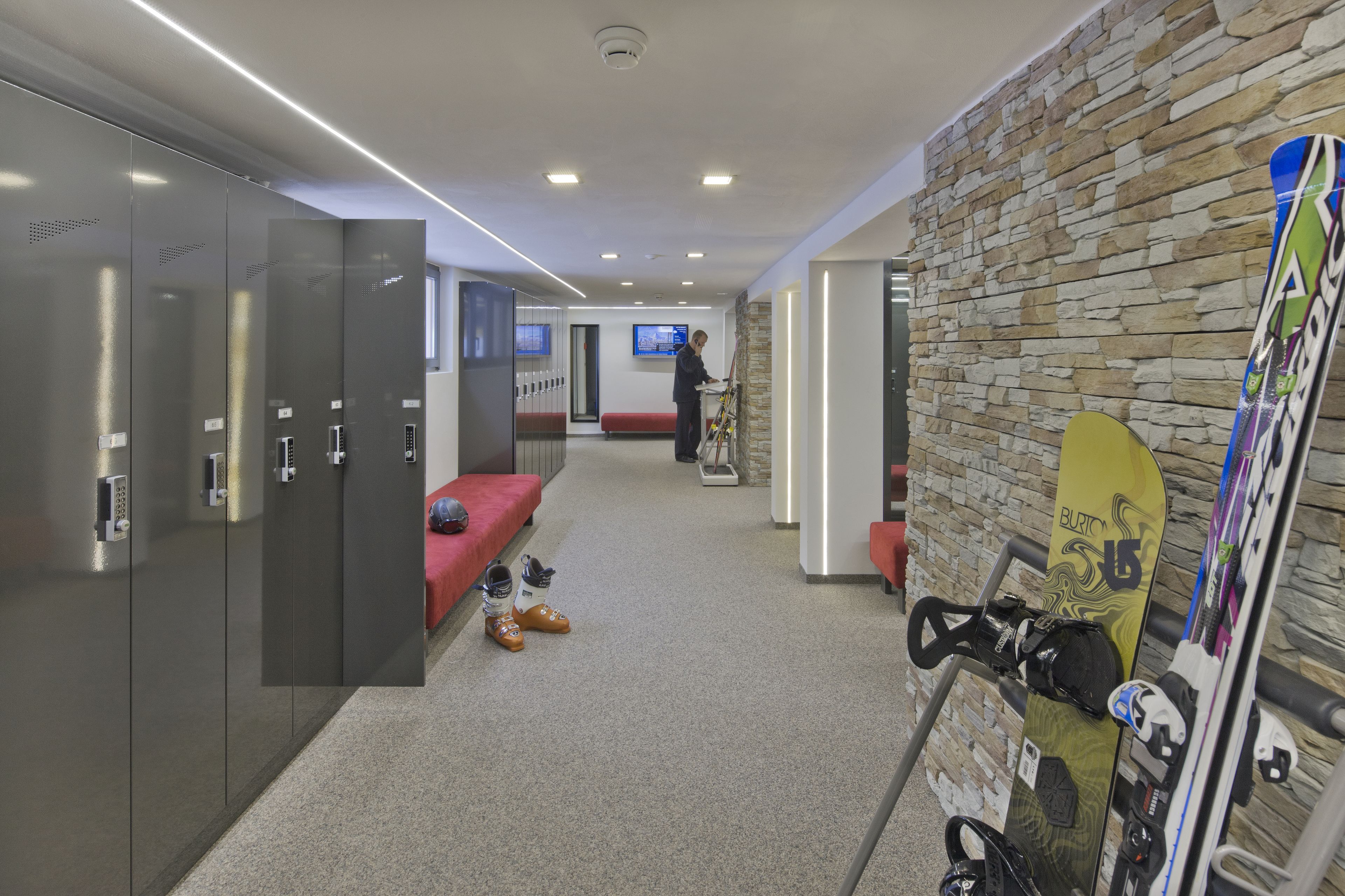 Um hall de hotel moderno com armários, área de estar e suporte para equipamento de esqui.