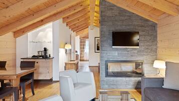 Ein modernes Interieur mit Holzbalkendecke, Kamin aus Stein und einem flachbildfernseher, der darüber angebracht ist.