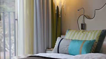 A hotel room with a bed, a nightstand, a lamp, and a view of the outdoors.