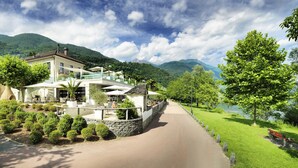 Um hotel moderno com área de pátio, rodeado por vegetação exuberante e montanhas.