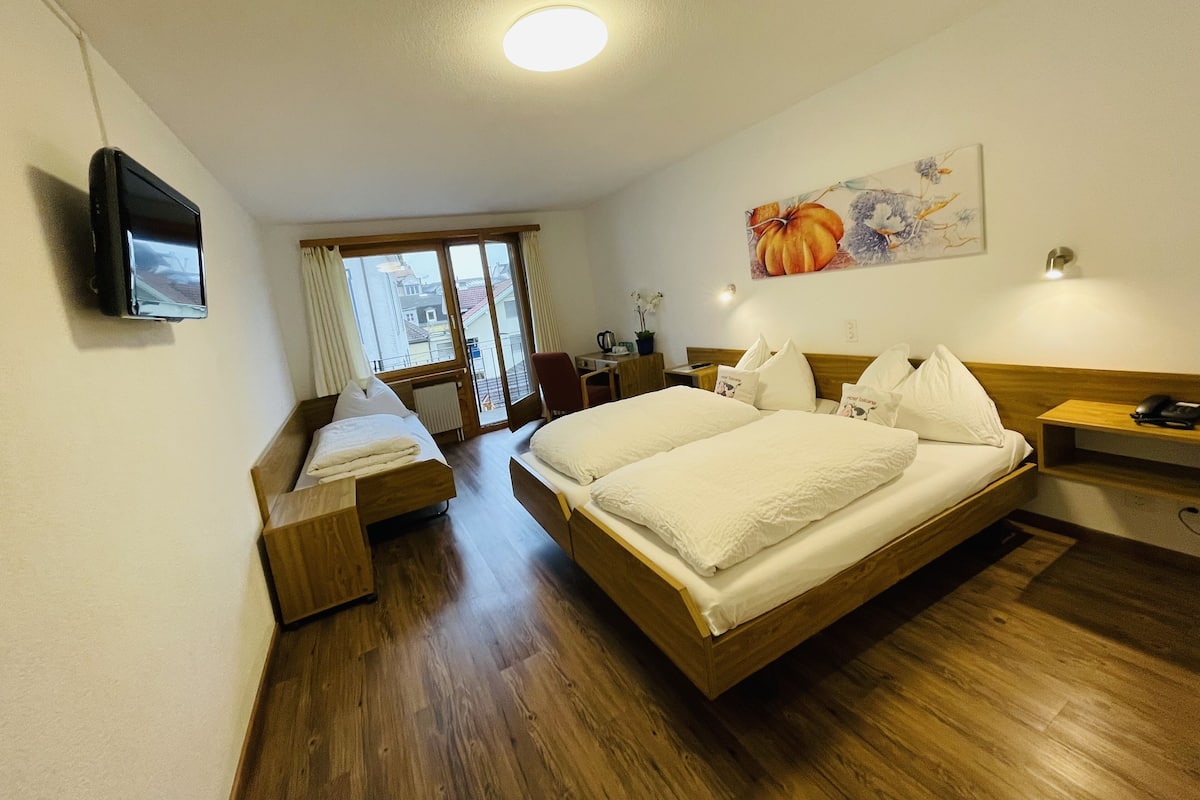 A hotel room with a large bed, a desk, a chair, a television, and a window with curtains.