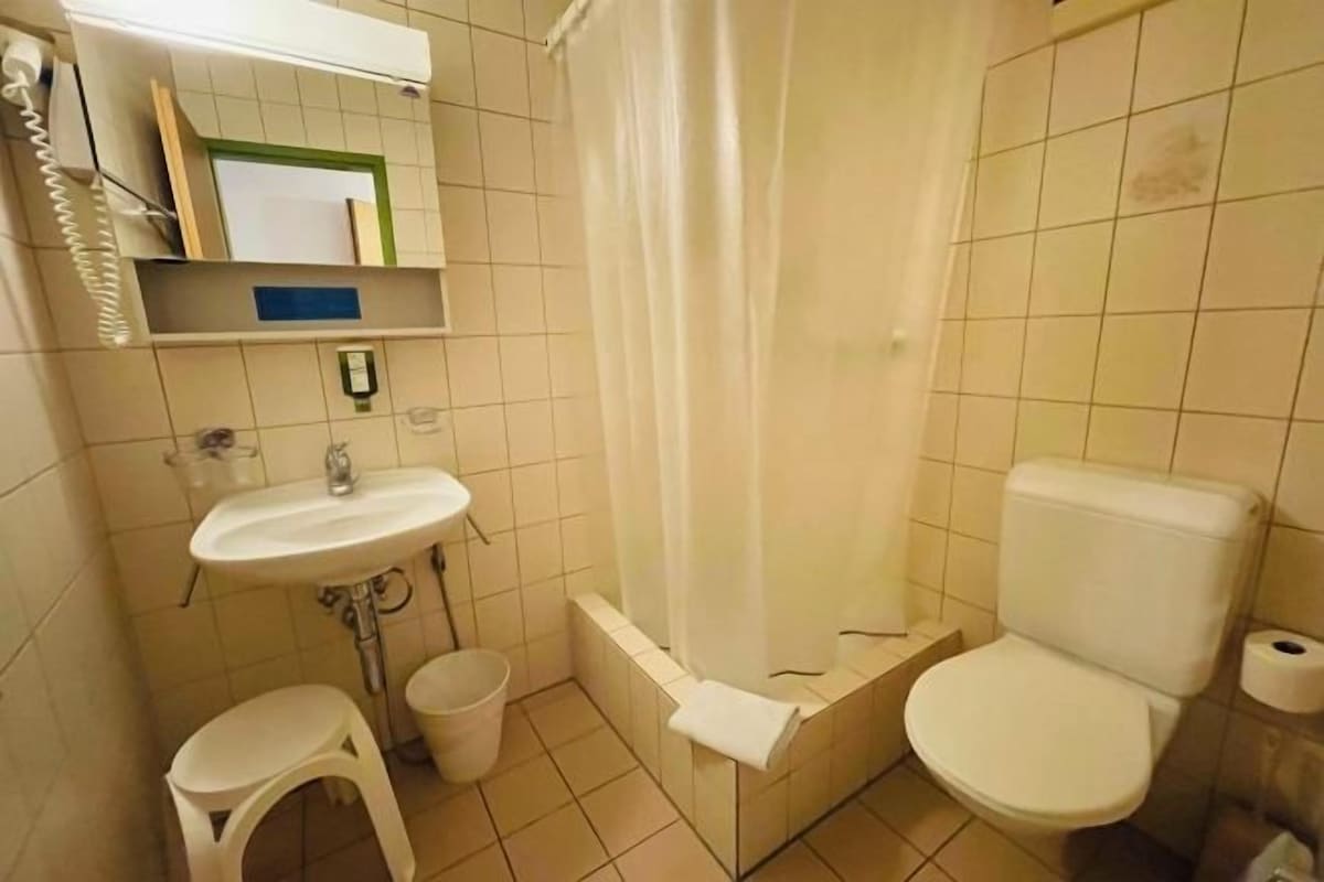 A small bathroom with a sink, toilet, and shower curtain.