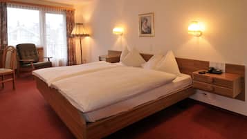 A hotel room with a large bed, two bedside tables, a chair, and a desk.