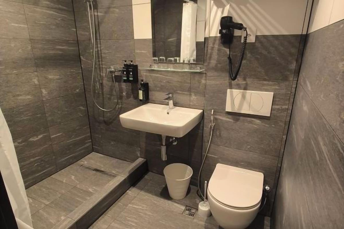 A modern bathroom with a shower, sink, toilet, and a glass partition.