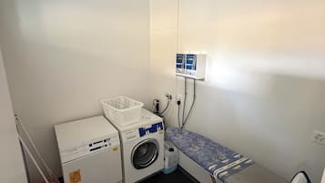 Ein kleiner Waschraum mit Waschmaschine, Trockner und Bügelecke.
