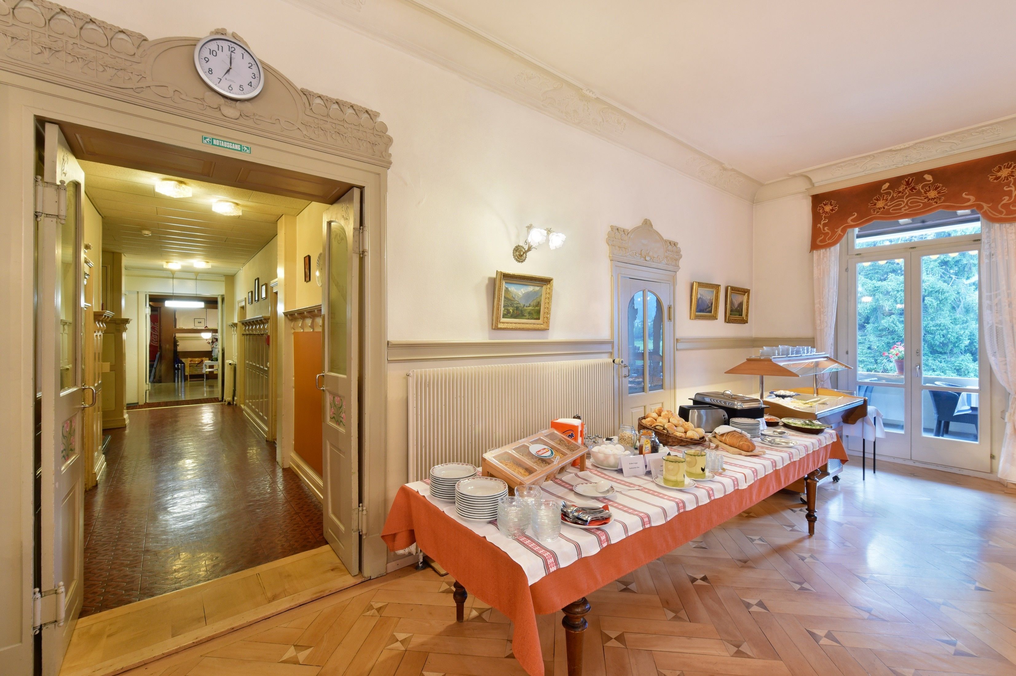 Un espace repas avec un buffet, une horloge et une vue sur l’extérieur.