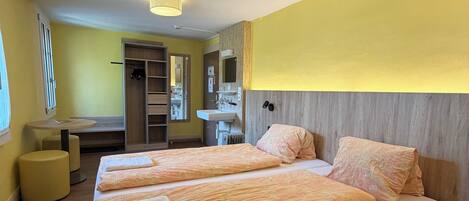 A hotel room with two beds, a bathroom, and a small seating area.