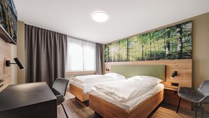 A hotel room with two beds, a desk, and a chair. - Hotel Linde (Baden)