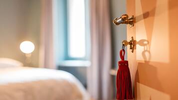 Une chambre d’hôtel avec un lit, une porte dotée d’une poignée en laiton et une frange rouge qui pend à la porte.