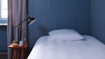 A bedroom with a bed, a nightstand, a lamp, and a window with curtains.