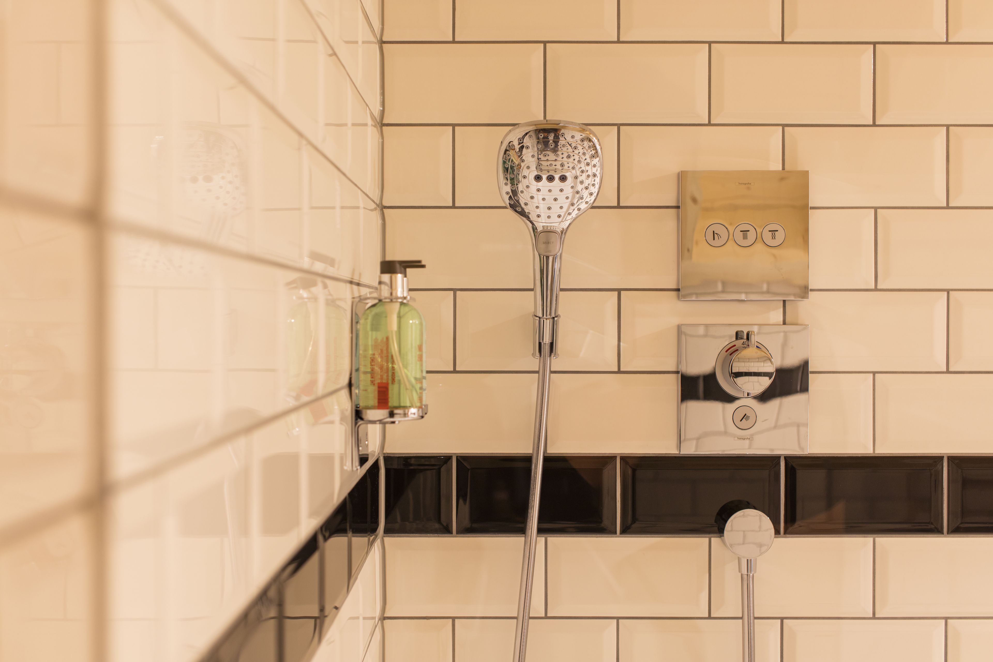 Une salle de bain équipée d’une douche, d’un distributeur de savon et d’un panneau de commande.