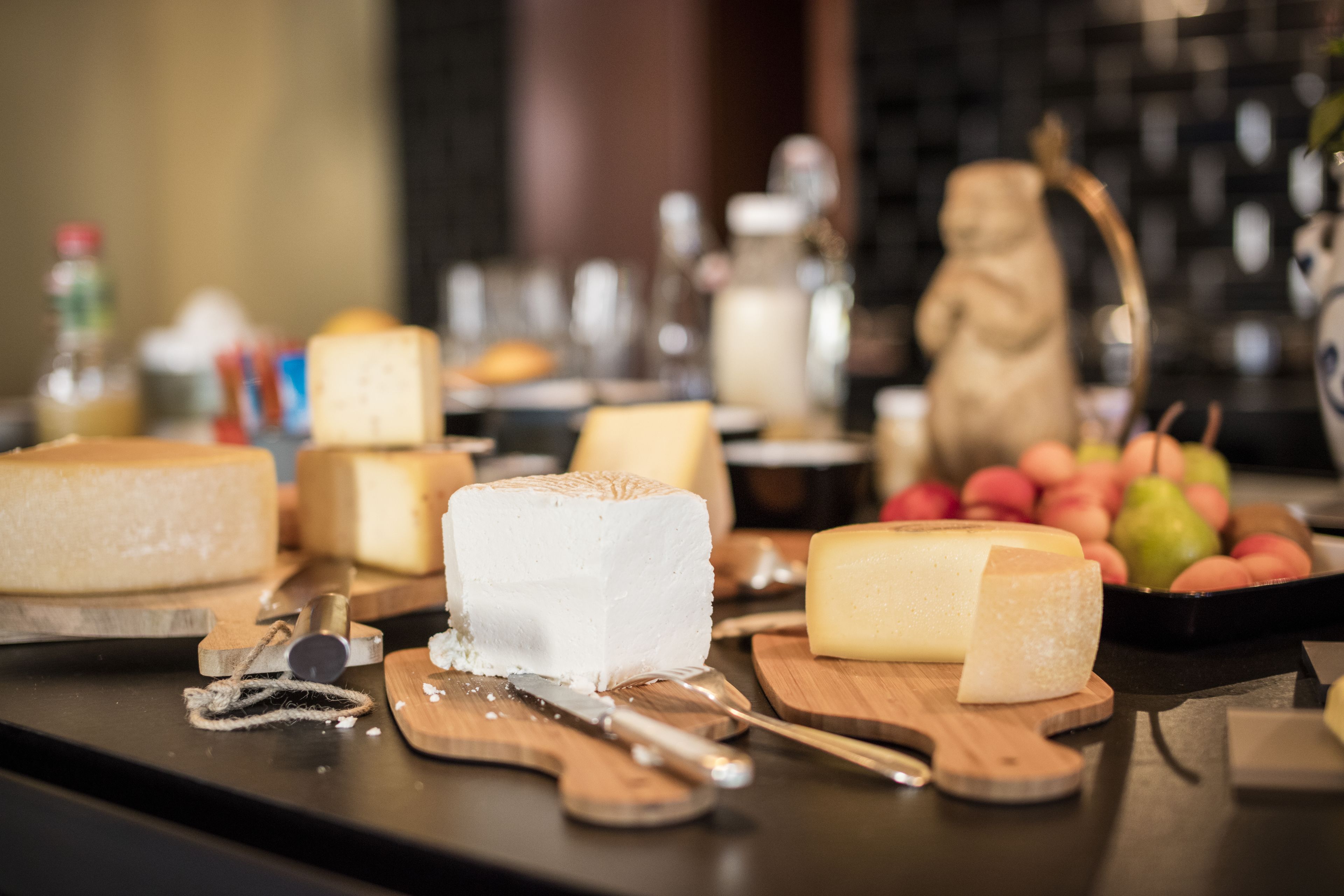 A cheese board with various types of cheese and a knife on a wooden board.