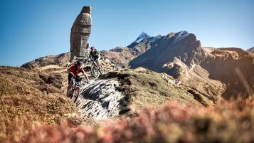 A mountain biking trail with a stone monument and a mountain in the background.
